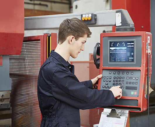 Apprentice inputting data into CNC metal press in steel fabrication factory